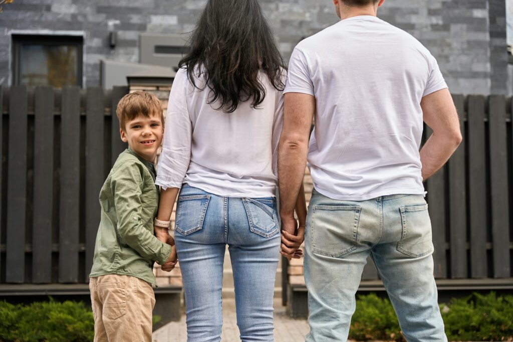 Child smiling at camera holding parent's hand