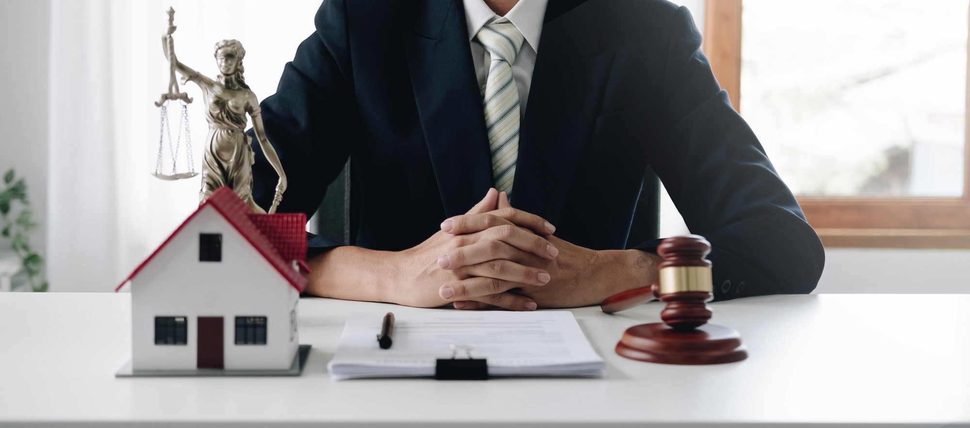 close-up photo of judge Wooden hammer and small wooden house on the table in the courtroom concept