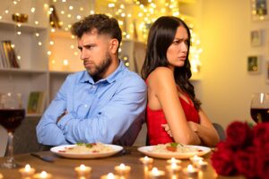 Displeased young couple at dinner, sitting back-to-back