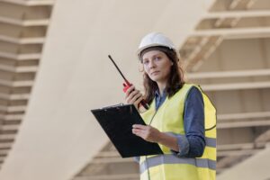 female engineer with a walkie-talkie at the construction site gives instructions. European