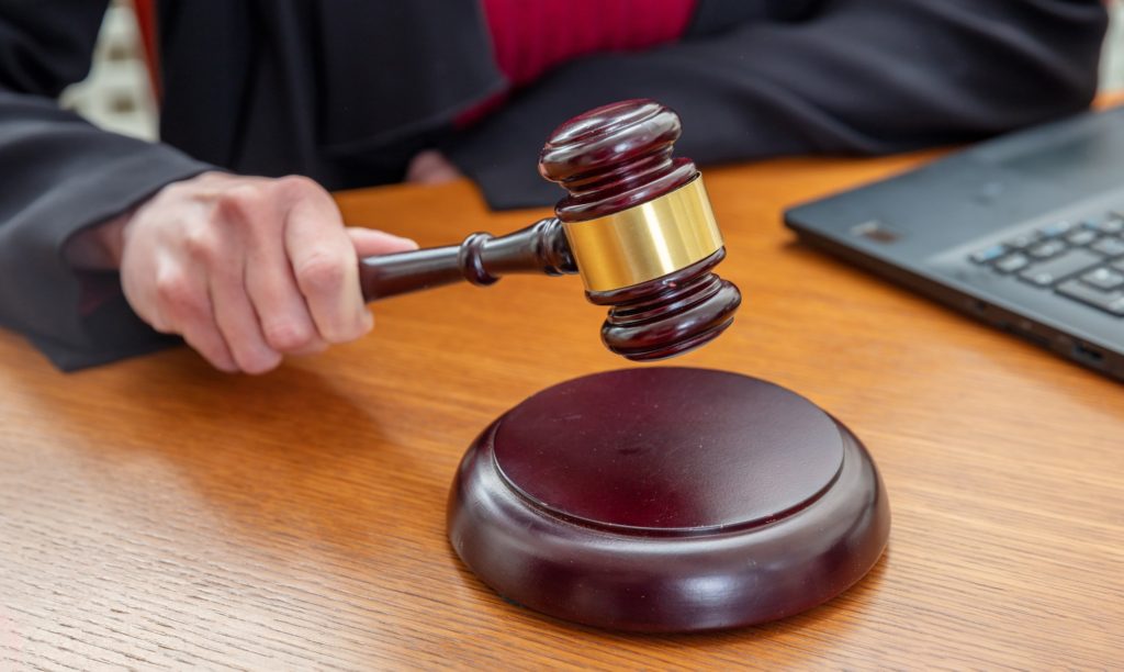 Online Auction, Law and technology concept. Woman with a laptop hold a judge gavel, close up