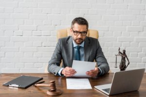 serious male judge working with papers and laptop in office