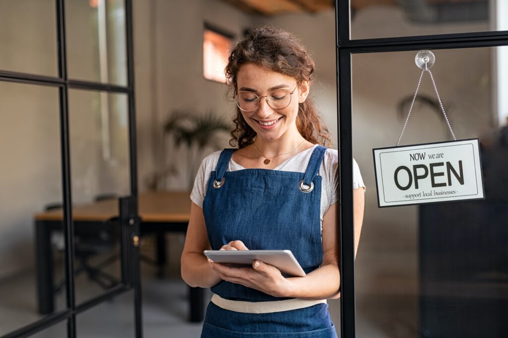 Small business owner using digital tablet at entrance